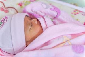 Newborn baby girl having a nap in co-sleeper crib attached to parents' bed photo