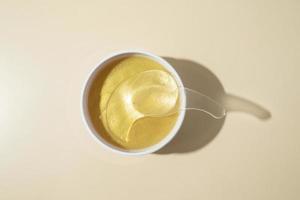 A white box of golden patches with snail standing on the beige background photo