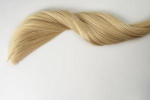 A strand of blonde hair lying on a white background photo