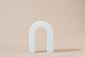 A white geometric shape in the form of the arch standing on a beige background photo