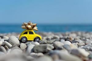 A yellow car with a bow on its top standing on the seaside photo