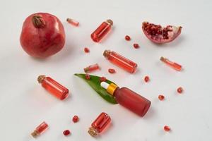 A pomegranate serum or oil lying on a white table photo