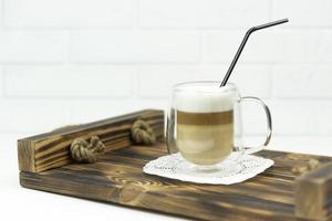 A cup of latte stands on a wooden tray for early breakfast photo
