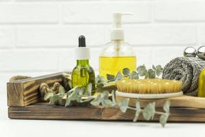 Face oil and face roller, brush for dry massage and a cotton towel lie on a wooden tray photo