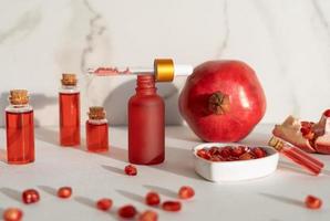 frascos cuentagotas rojos de suero o aceite de granada para la cara y el cuerpo sobre un fondo blanco foto