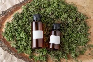 Dropper bottles of serum or oil with vitamin C  with blank labels lying on a moss photo