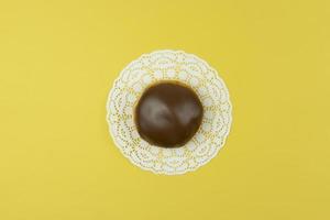 A tasty glazed donut lies on a yellow background photo