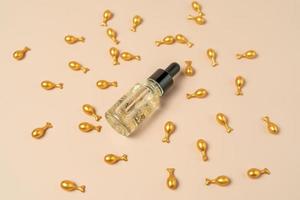 A face serum or oil in golden capsules lying on a beige background photo