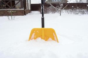 A yellow shovel standing in the snow photo