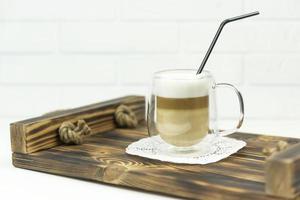 A cup of latte stands on a wooden tray for early breakfast photo