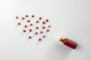 A red dropper bottle of pomegranate serum or oil lying on a white background photo