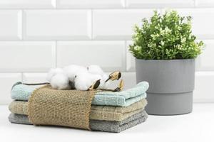 Cotton towels of neutral colours with a branch of cotton on them lie on a table in a modern bathroom photo