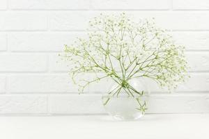 ramas frescas de flores blancas de gypsophila en un jarrón de vidrio. la primavera está llegando foto