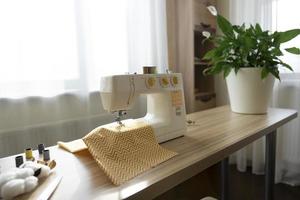 A white sewing machine stands on the table photo