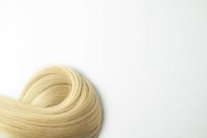 A strand of blonde hair lying on a white background photo