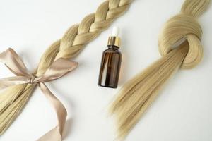 cabello rubio natural y aceite esencial para el tratamiento del cabello sobre un fondo blanco foto