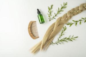 aceite natural o suero de cabello cbd que se encuentra cerca de la trenza de cabello rubio sobre un fondo blanco foto