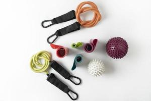 Different colourful equipment for fitnes and sport exercises balls, bands and expanders lying on a white floor photo