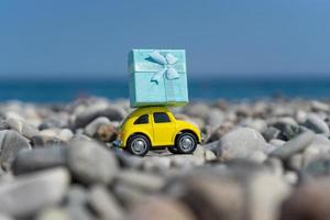 A yellow car carrying a blue present on its top as a delivery concept photo