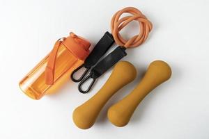 diferentes equipos coloridos para ejercicios de fitness y deportivos mancuernas y expansores naranjas, pelotas de fitness y bandas sobre un fondo blanco foto