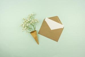 Spring is coming concept. A blank in a brown envelope with fresh flowers in a waffle cone. Mock up photo