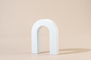 A white geometric shape in the form of the arch standing on a beige background photo