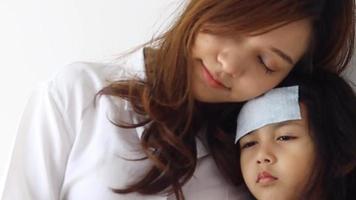 Asian mother caring for a sick daughter in bedroom, family love and encouragement concept video