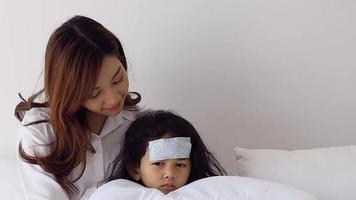 Asian mother caring for a sick daughter in bedroom, family love and encouragement concept