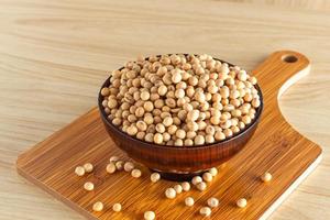 soybean in a bowl with wooden chopping board on wooden background, front view, selective focus. photo