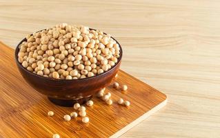 soybean in a bowl with wooden chopping board and spoon on wooden background, front view, selective focus. photo