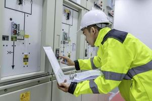 ingeniero eléctrico revisando el voltaje en el gabinete de distribución de energía en la sala de control, mantenimiento preventivo anual, electricista tailandés trabajando en la empresa foto