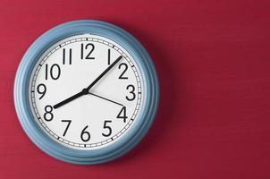Blue wall clock on red grunge background. photo