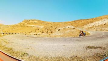 Back view close up cyclist on bicycle touring bicycle rides fast downhill outdoors in scenic mountains photo