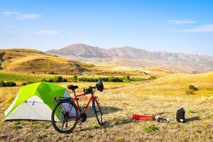 Panorama of unloaded touring red bicycle by green tent. Camping and bicycle touring concept Travel around Armenia by bicycle in mountains in autumn photo