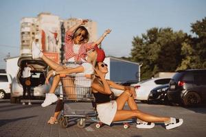 las mujeres jóvenes con un carrito de supermercado se divierten foto