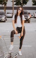 Young and happy woman put leg inside a shopping cart photo