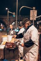 anciano cocinando salchichas en la calle foto