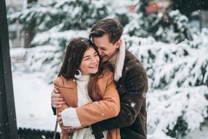 young guy hugs a beautiful girl in the snowy park photo