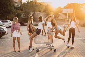 las mujeres jóvenes con un carrito de supermercado se divierten foto