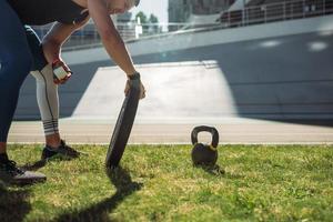 Young guy raises iron plate in the stadium, outdoor workout photo