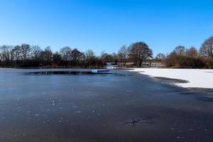 Snow covered frozen lake landscape in northern europe on a sunny day. photo