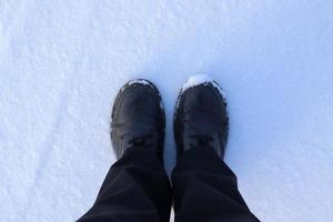 High angle view at black boots standing in fresh snow. photo