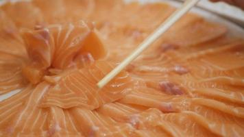 usa palillos para elegir un trozo de sashimi de salmón fresco en un restaurante japonés video