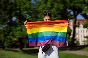 mujer joven sosteniendo una bandera del orgullo lgbt en sus manos. foto