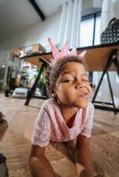 Little girl sitting on the floor grimacing at the camera photo