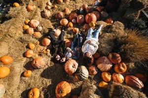 Young girls lie on haystacks among pumpkins. View from above photo