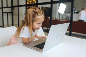 niña usando una computadora de tableta sentada en la mesa foto