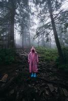 Young woman in a raincoat walks through the forest in the rain photo