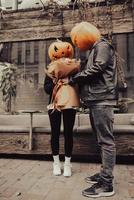 The guy gives his girlfriend a bouquet, both with a pumpkin head photo