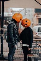 Guy and girl with pumpkin heads look at each other photo